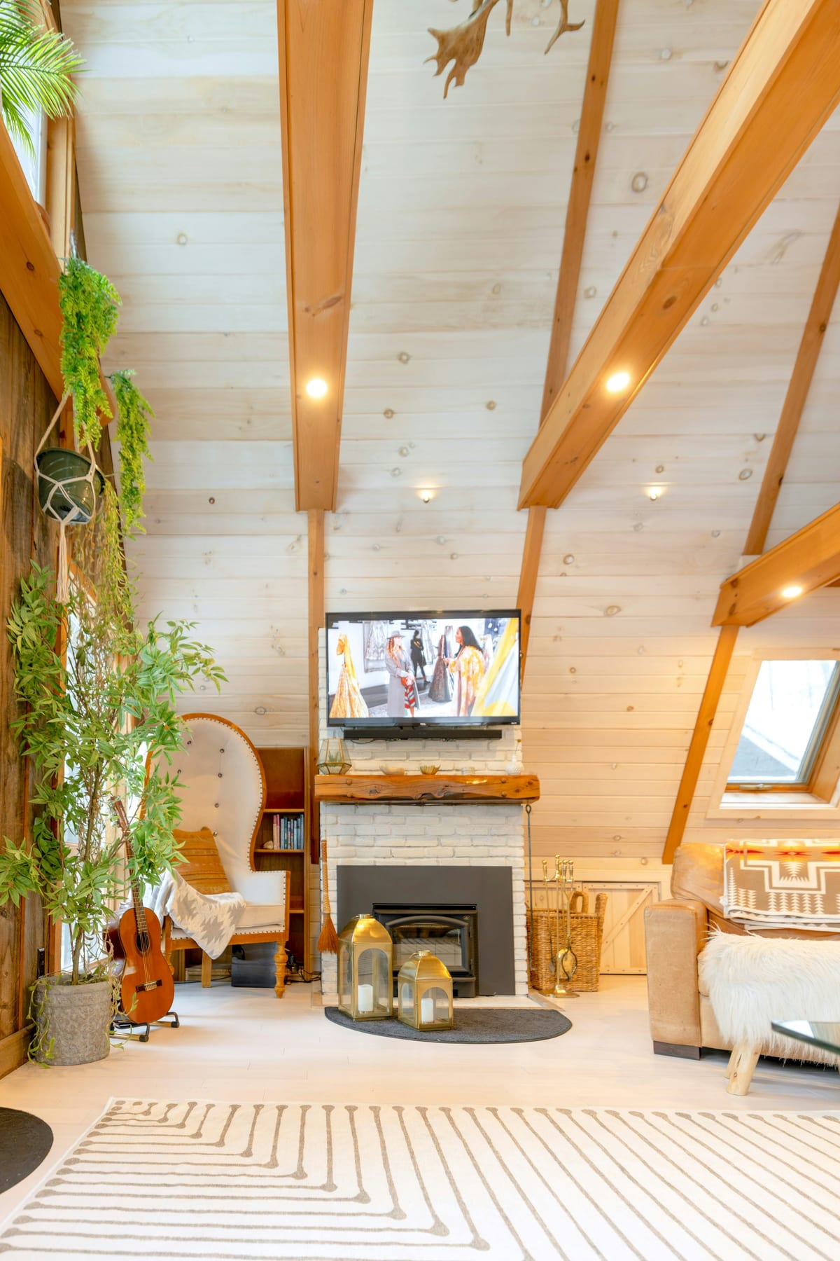 Bright residential living room with a high vaulted cathedral ceiling featuring angled roof slopes and exposed wood beams